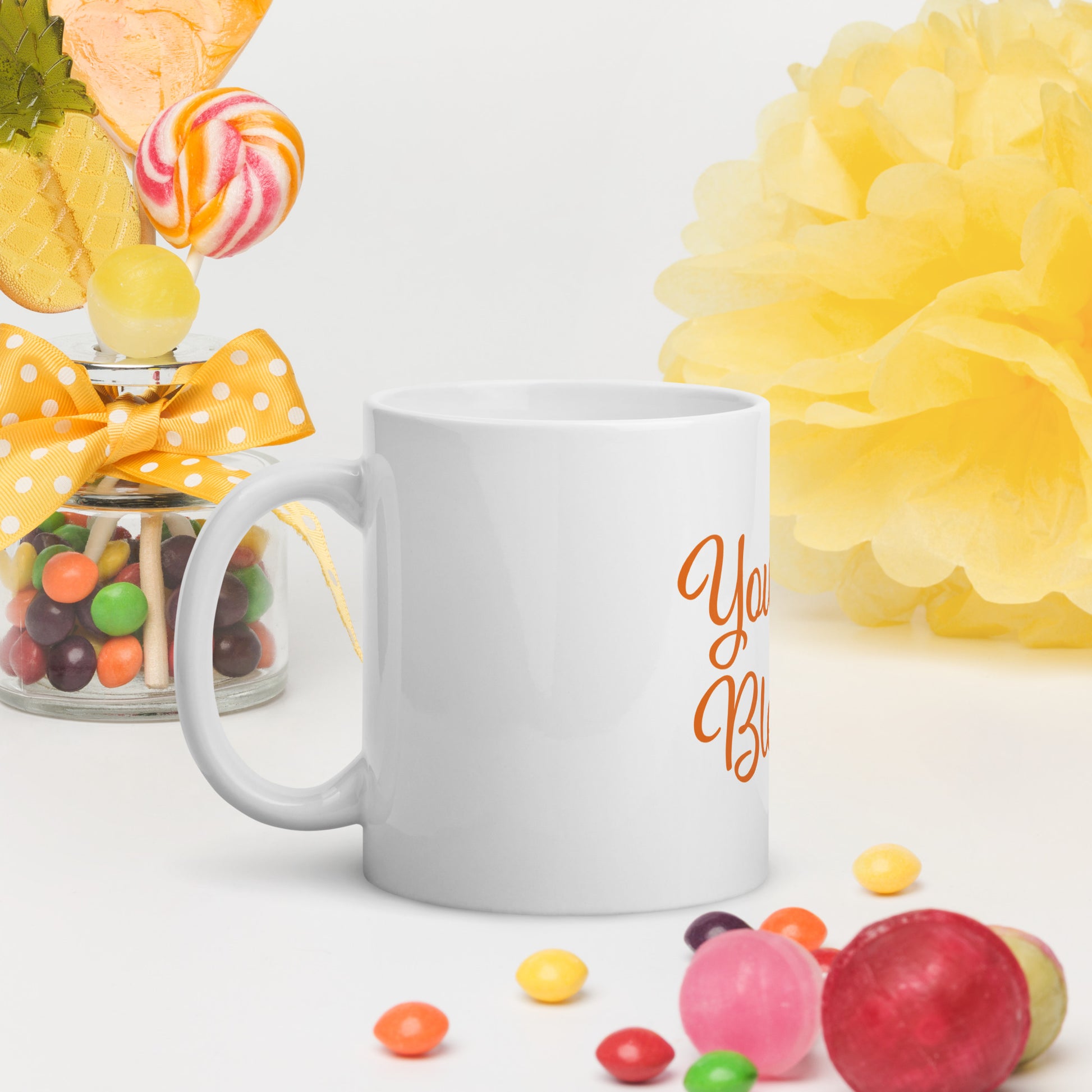 White mug with You Are Blessed text, surrounded by colorful candies and flowers on a white background.